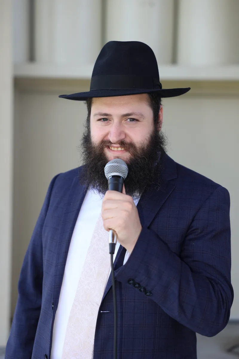 Portrait of Motty Reizes holding a microphone